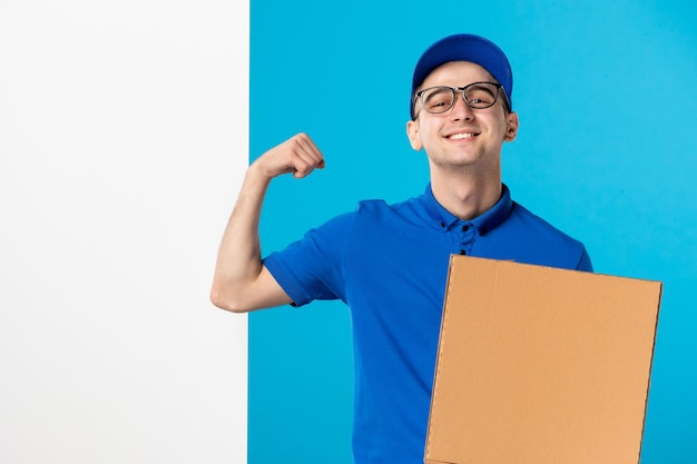 Foto vista frontal do mensageiro masculino sorridente com uniforme azul e pizza no azul