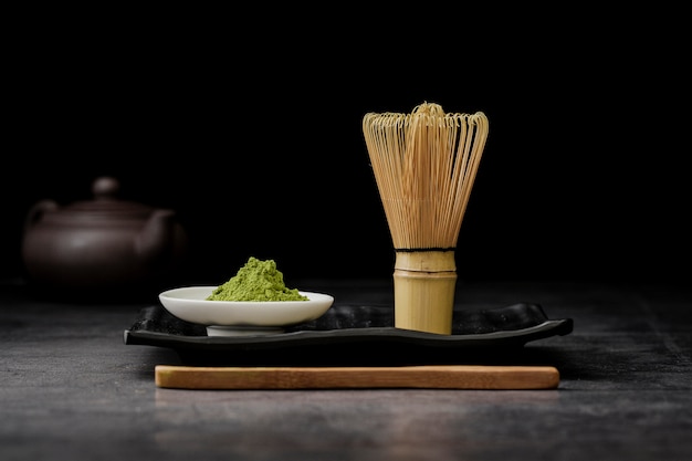 Vista frontal do pó de chá matcha com batedor de bambu