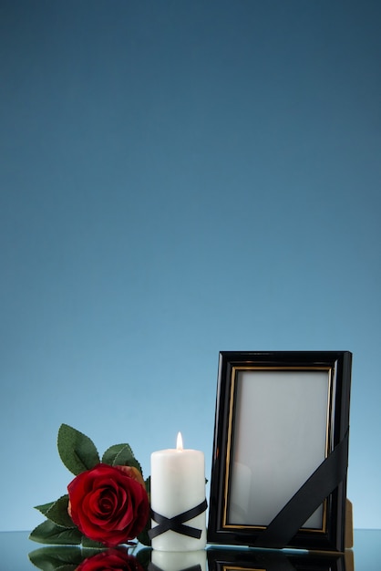 Foto vista frontal do porta-retratos com flor vermelha no chão azul, funeral da morte da guerra do mal