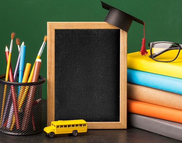 Foto vista frontal do quadro-negro com tampa acadêmica e pilha de livros