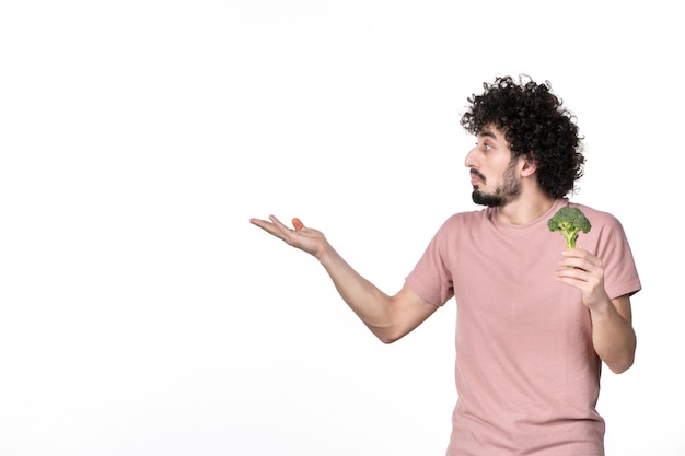 Vista frontal do sexo masculino jovem segurando um pequeno brócolis verde no fundo branco corpo horizontal vegetal dieta humana saúde salada peso cor