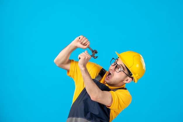 Vista frontal do trabalhador masculino de uniforme amarelo com um alicate azul