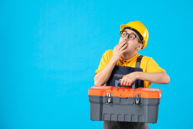 Vista frontal do trabalhador masculino em uniforme amarelo com caixa de ferramentas em azul