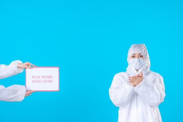 Vista frontal doctora en traje de protección y máscara sobre fondo azul aislamiento de enfermedades covid ciencia salud virus pandemia médica