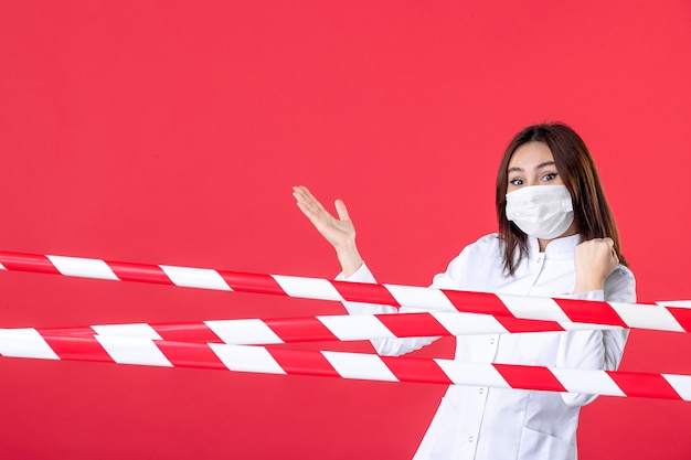 Vista frontal de la doctora en uniforme médico y máscara sobre fondo rojo salud sellada virus del crimen línea del hospital covid