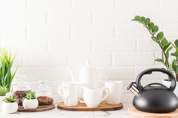 Vista frontal de la encimera con una bandeja con una cafetera tazas latas de café al final de la decoración de la cocina casera cocina ecológicamente limpia