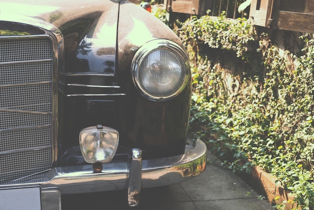 Foto vista frontal (farol dos faróis) do carro clássico estacionado na estrada - estilos de efeito de cor retro vintage