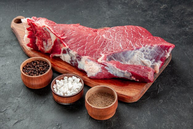 Vista frontal fatia de carne crua com sal e pimenta em fundo escuro cozinhar açougueiro prato comida carne jantar refeição churrasco cor