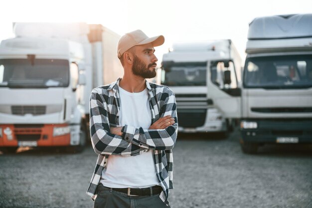 Foto vista frontal en gorra joven camionero está con su vehículo durante el día