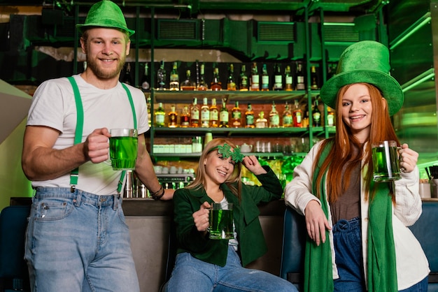 Foto vista frontal del grupo de amigos celebrando st. patrick's day en el bar con bebidas