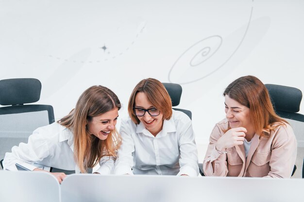 Foto vista frontal del grupo de mujeres de negocios en ropa formal en el interior de la oficina