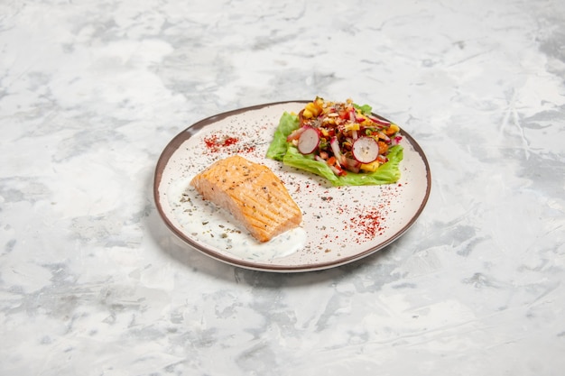 Vista frontal de la harina de pescado y una deliciosa ensalada en un plato sobre una superficie blanca manchada con espacio libre