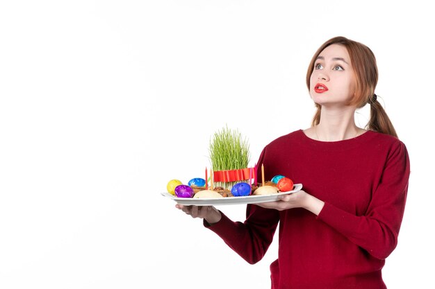 Vista frontal hembra joven con honca con semeni y dulces novruz sobre fondo blanco ejecutante étnico colores de vacaciones concepto de etnia familia