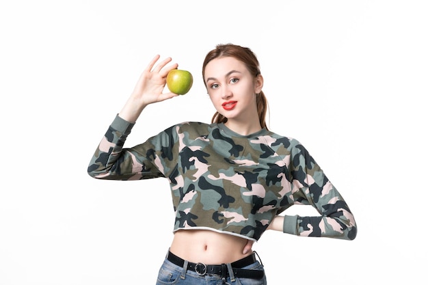 Vista frontal hembra joven sosteniendo manzana verde fondo blanco comida colores plato de jugo humano árbol de comida pistola dieta tiro fruta