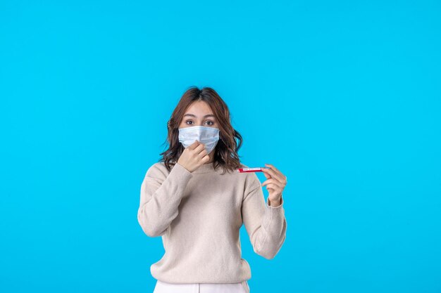 Vista frontal de las hembras jóvenes en máscara con matraz sobre el fondo azul ciencia enfermedad médica virus covid pandemia aislamiento de salud