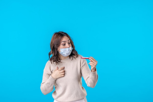 Vista frontal de las hembras jóvenes en máscara con matraz sobre el fondo azul ciencia enfermedad médica virus covid pandemia aislamiento de salud