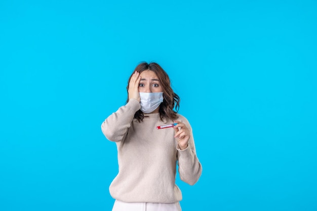 Vista frontal de las hembras jóvenes en máscara con matraz sobre fondo azul virus médico covid pandemia ciencia salud aislamiento