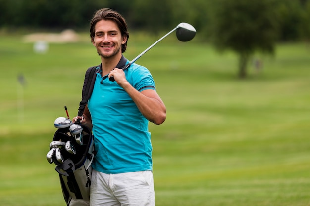 Vista frontal hombre adulto con palos de golf