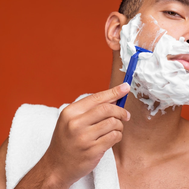 Foto vista frontal del hombre afeitándose la barba con navaja