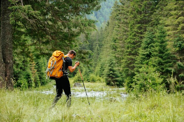 vista frontal de hombre americano caucásico al aire libre haciendo senderismo usando palos de caminar en el campo turista masculino mirando lejos estilo de vida activo viajes aventuras vacaciones puesta de sol