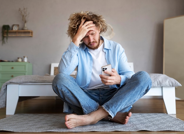 Foto vista frontal hombre ansioso con teléfono inteligente