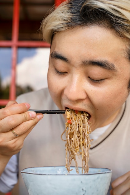 Foto vista frontal hombre comiendo fideos