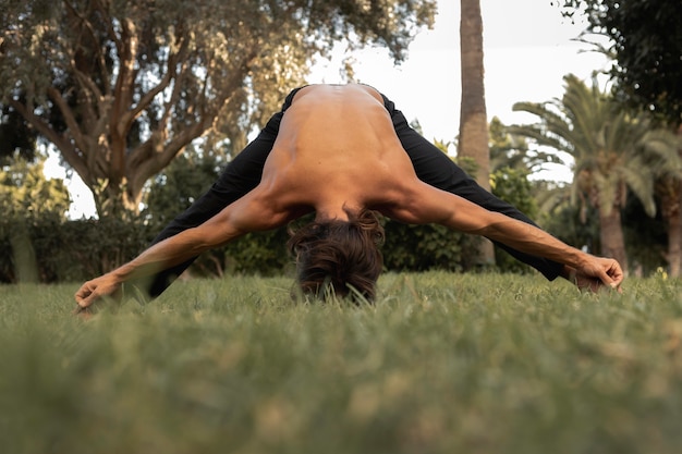 Foto vista frontal del hombre haciendo yoga en la hierba