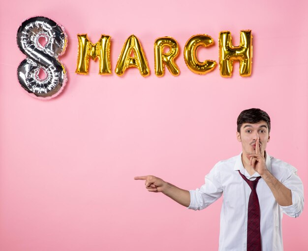 Vista frontal hombre joven con decoración de marzo sobre fondo rosa matrimonio fiesta igualdad hombre femenino día de la mujer presenta color