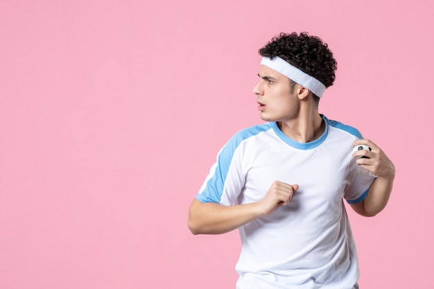 Vista frontal del hombre joven en ropa deportiva en la pared rosa