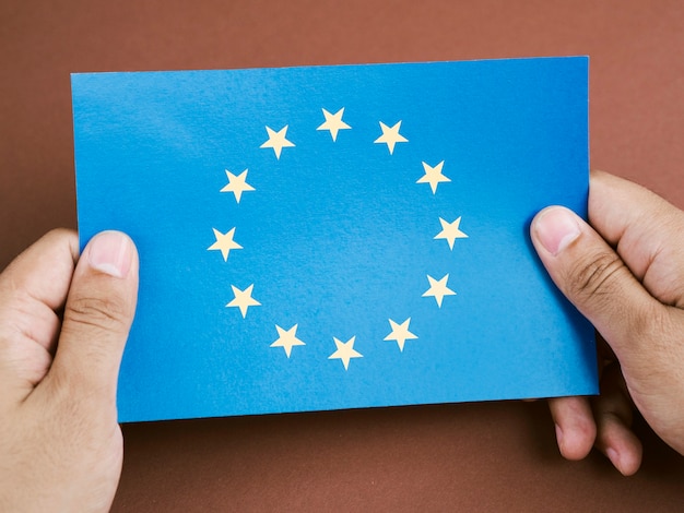 Vista frontal hombre sosteniendo una tarjeta con la bandera de la Unión Europea