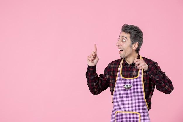 Vista frontal de los hombres jóvenes en el cabo sosteniendo una cuchara de sopa de plata sobre fondo rosa trabajador horizontal profesión alimentaria marido cocina cocina cocinero
