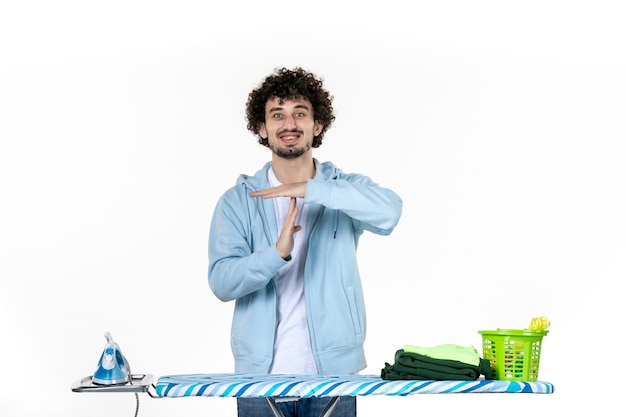 Vista frontal de los hombres jóvenes detrás de la tabla de planchar haciendo t firmar sobre fondo blanco ropa hombre lavandería foto limpieza de color quehaceres domésticos de hierro