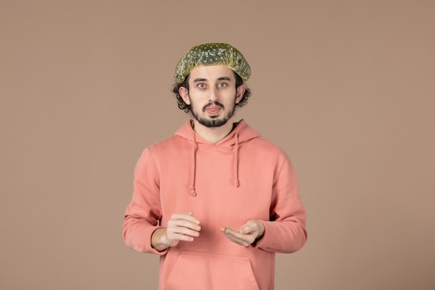 Vista frontal de los hombres jóvenes con gorro bouffant sobre fondo marrón cuidado de la piel masaje spa terapia de la piel salón de cabello facial