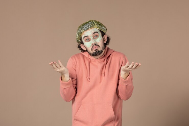 Foto vista frontal de los hombres jóvenes con gorro y máscara bouffant en su rostro sobre fondo marrón salón de terapia de cuidado de la piel cabello facial spa piel