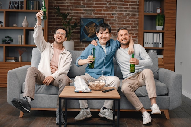 Vista frontal de hombres viendo un partido de fútbol en la televisión y bebiendo una cerveza