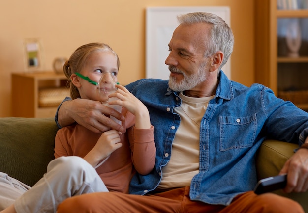 Foto vista frontal homem e menina com nebulizador