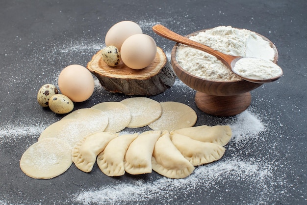 Vista frontal de hotcakes de patata cruda con huevos y harina sobre un fondo oscuro para cocinar masa para tartas horno de galletas para hornear alimentos para hornear