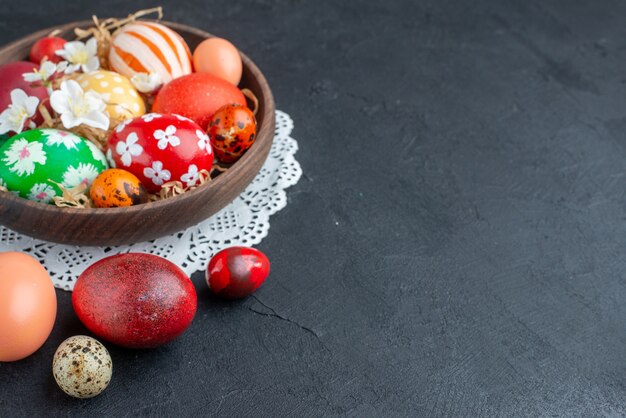 Vista frontal de los huevos de colores diseñados dentro de la placa marrón fondo oscuro vacaciones coloridas novruz primavera ornamentada