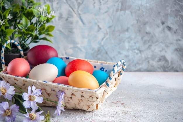 Vista frontal de los huevos de pascua de colores con una bonita caja diseñada sobre un fondo blanco, varios colores de primavera, grupo de colores ornamentados