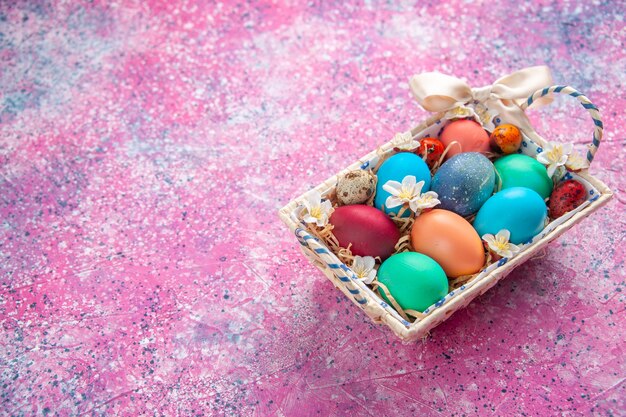 Vista frontal de los huevos de pascua de colores dentro de una bonita caja en la superficie rosada concepto de color de primavera coloridas vacaciones de pascua