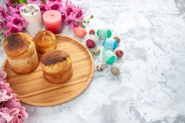 Vista frontal de huevos de pascua de colores con flores y pasteles sobre fondo blanco color colorido primavera novruz concepto ornamentado