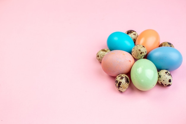 Vista frontal de los huevos de pascua de colores sobre la superficie rosada colorida primavera color vacaciones pascua concepto ornamentado