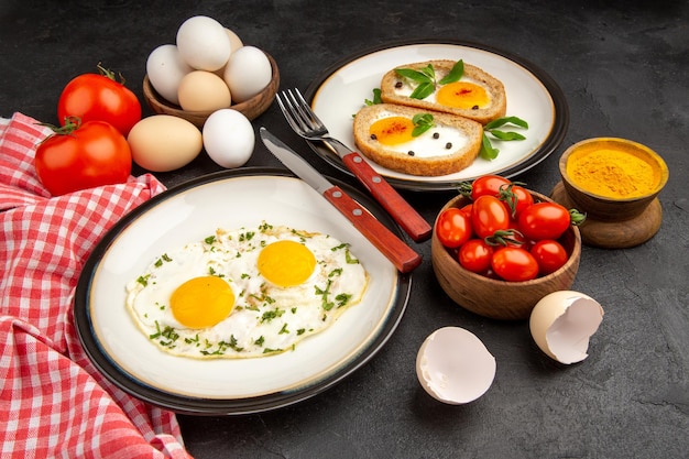 Vista frontal huevos revueltos con tostadas y tomates sobre fondo gris tortilla de pan comida desayuno almuerzo té comida mañana