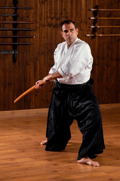 Foto vista frontal del instructor de artes marciales masculino en la sala de práctica