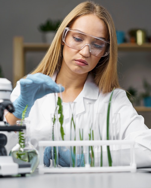 Vista frontal de la investigadora con tubos de ensayo y microscopio