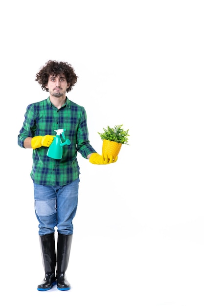 Vista frontal jardinero masculino sosteniendo pequeña planta sobre fondo blanco trabajo de campo de tierra árbol cavar flor hierba hoja jardín agua