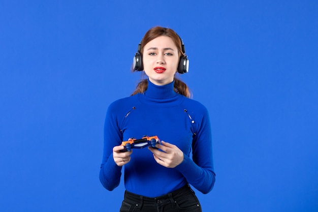 vista frontal jogador feminino com fones de ouvido e gamepad no fundo azul jovem vídeo alegria sofá jovem virtual jogador adulto