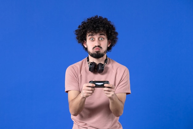 vista frontal jogador masculino jogando videogame com gamepad no fundo azul jogador de vídeo adulto virtual jovem futebol adolescente vencendo