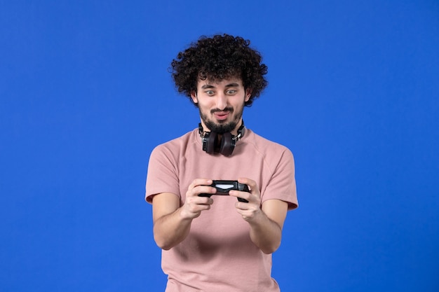 vista frontal jogador masculino jogando videogame com gamepad no fundo azul jogadores virtuais de alegria de vídeo adulto jovem futebol adolescente vencendo