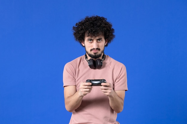 vista frontal jogador masculino jogando videogame com gamepad no fundo azul jovem adolescente virtual ganhando juventude vídeo futebol adulto alegria